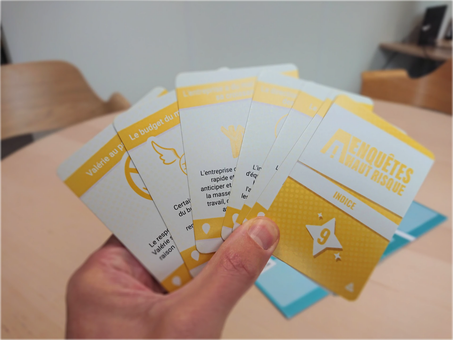 Main d'un participant tenant des cartes indices lors d'une session de serious game EAHR pour analyser un scénario de risque professionnel.